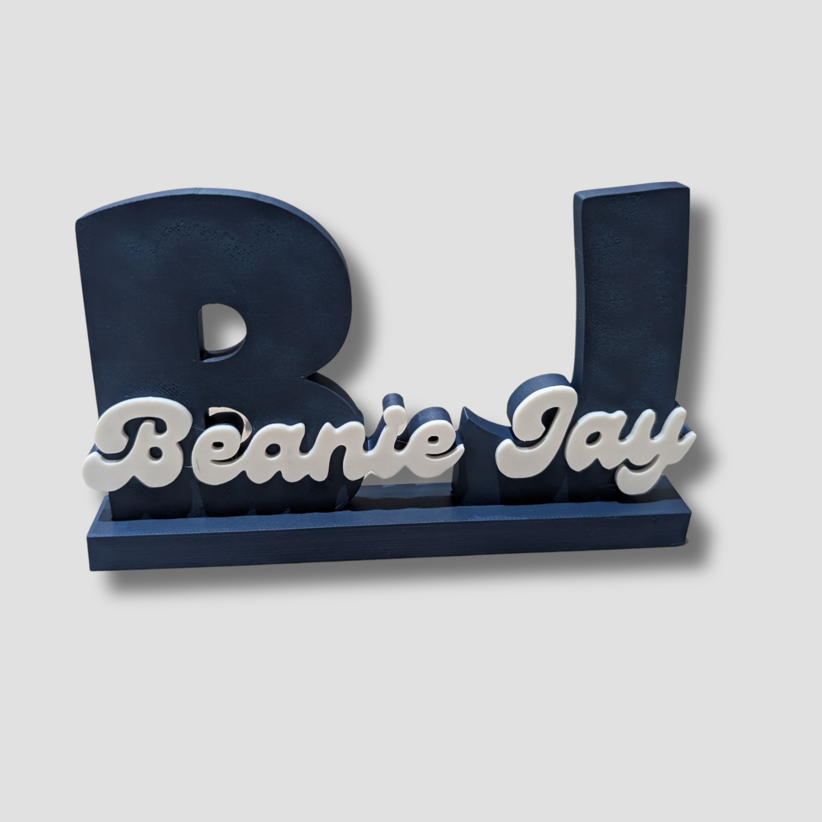 Navy blue and white decorative letter 'B' with 'Beanie Jay' text on a light gray background