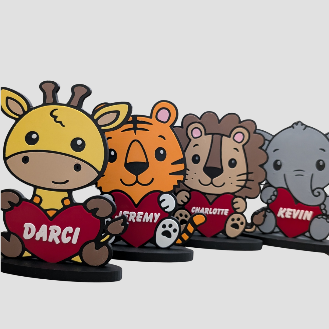 Group photo of four personalised safari animal ornaments: Giraffe (Darci), Tiger (Jeremy), Lion (Charlotte), and Elephant (Kevin), all holding a red heart.