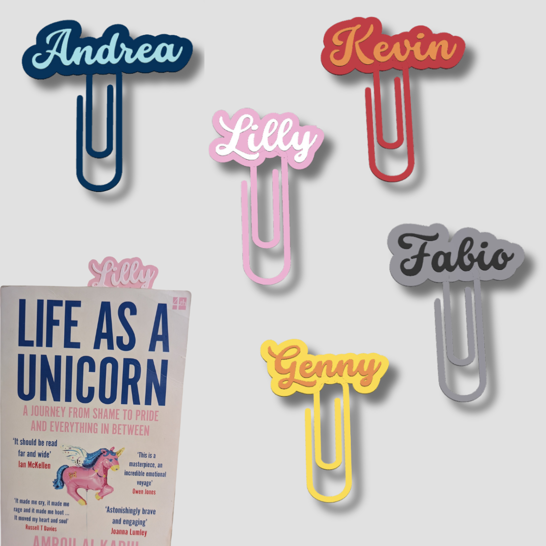 Group of five personalised paperclip bookmarks in various colours, including names Andrea, Kevin, Lilly, Fabio, and Genny, marking a book page.