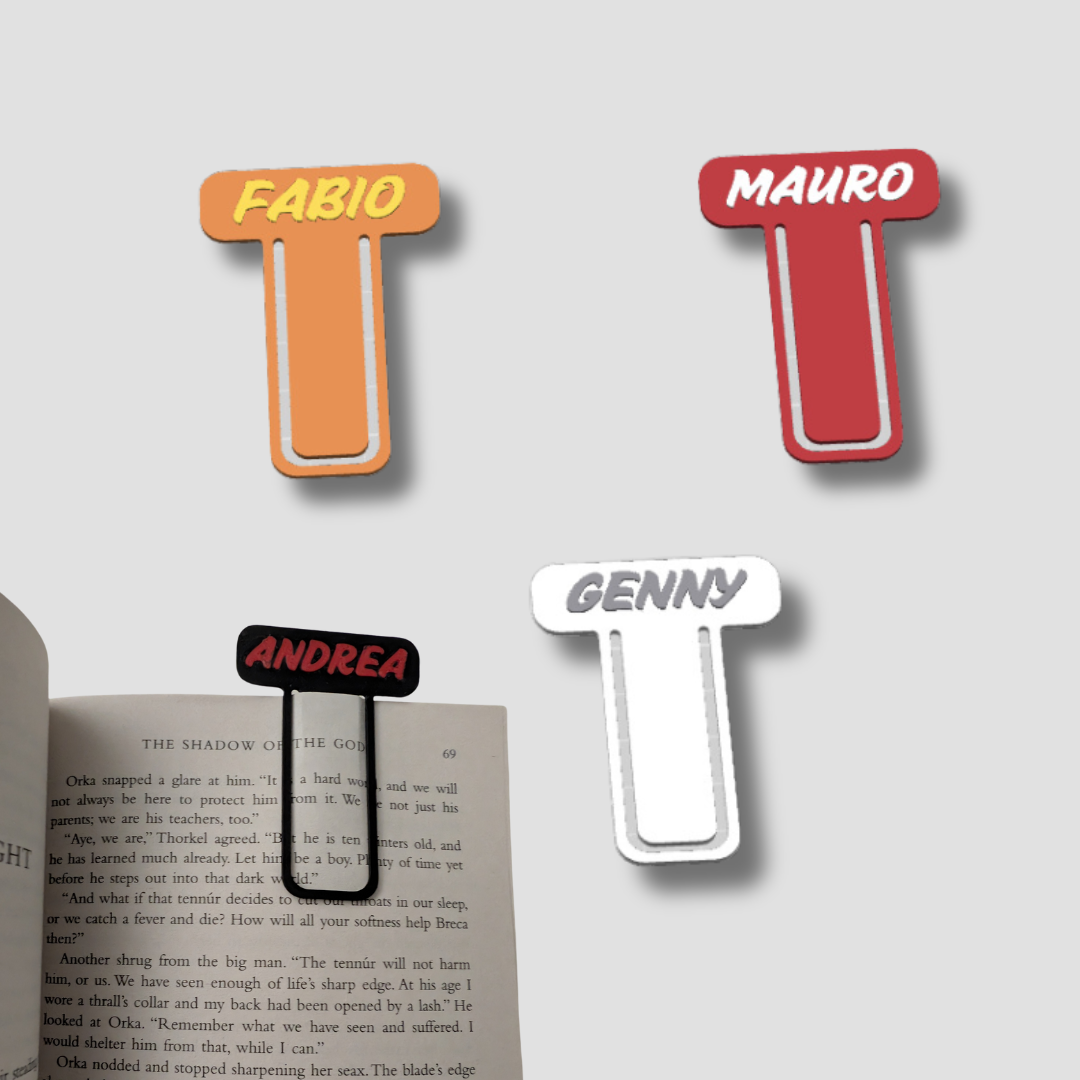 Group of four personalised initial bookmarks in red, orange, black, and white with names Fabio, Mauro, Andrea, and Genny, marking a book page.