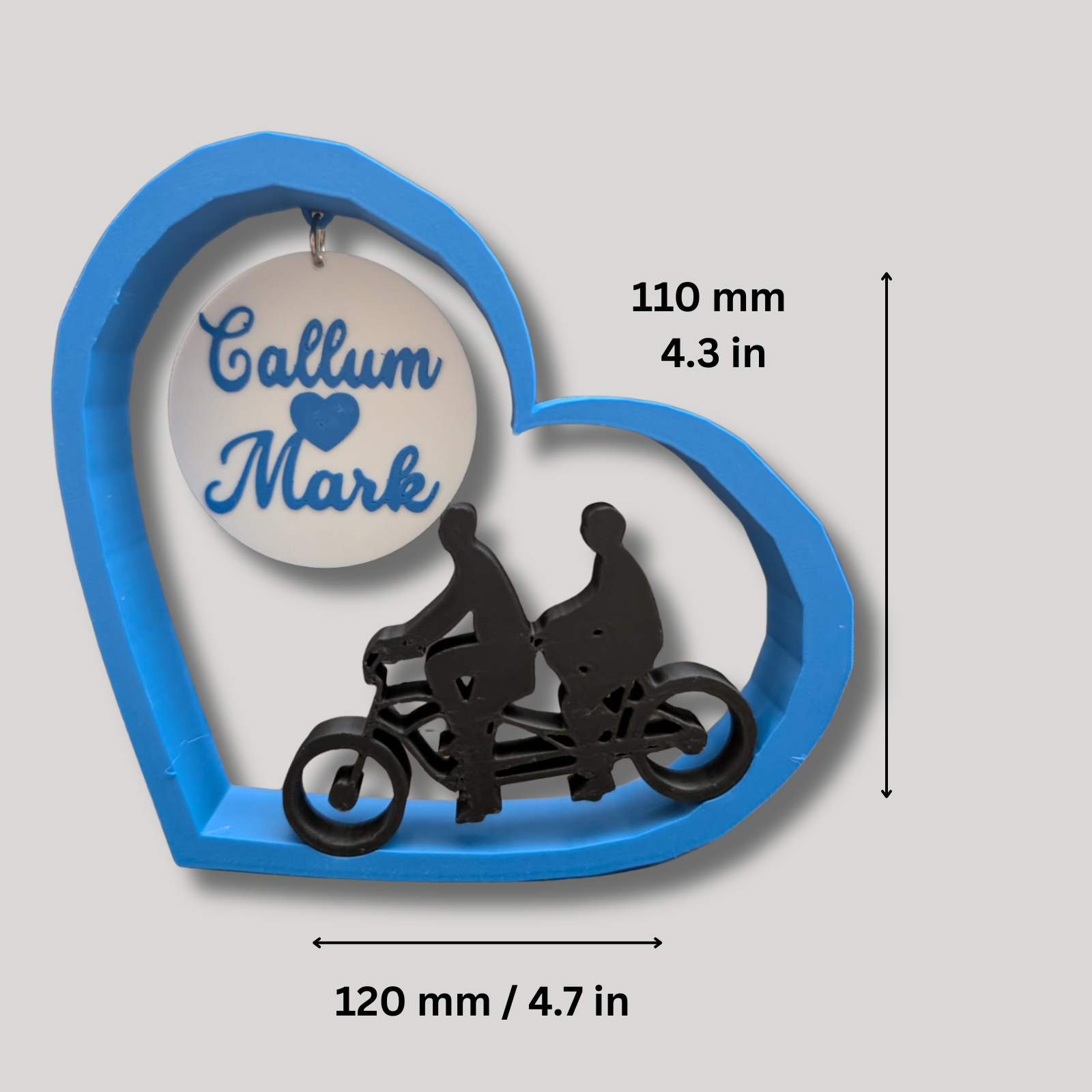 Heart-shaped decorative item with two silhouettes men on a motorcycle and text