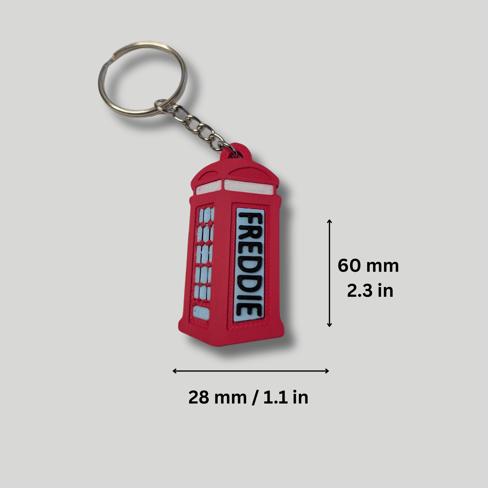 Red keychain with 'FREDDIE' text, shown with measurements on a gray background