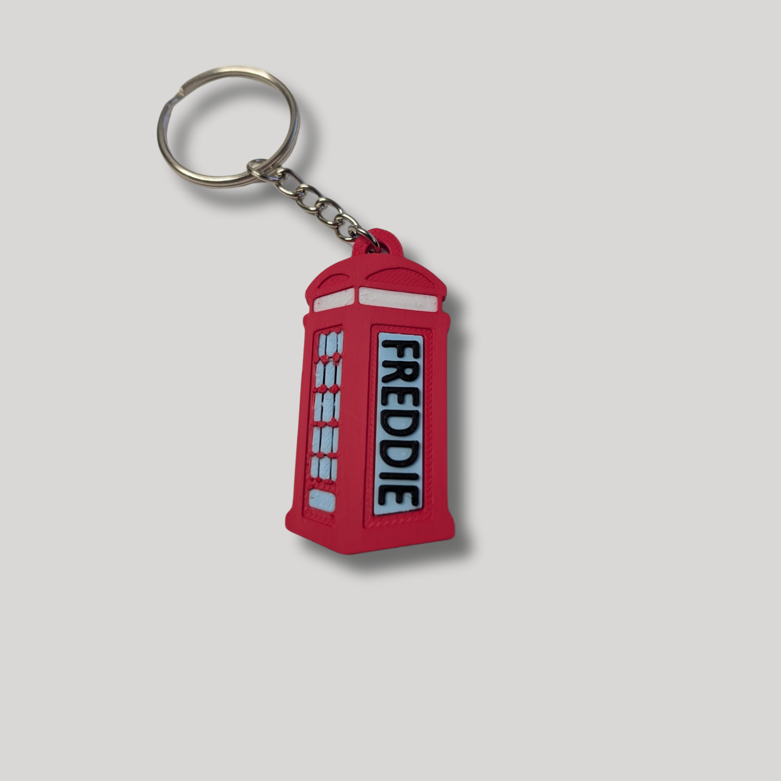 Red phone booth keychain with 'FREDDIE' on a gray background