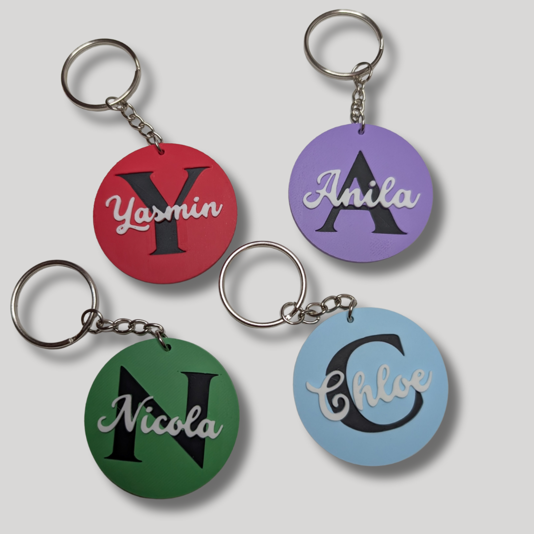Four keychains with names 'Yasmin', 'Anila', 'Nicola', and 'Chloe' on colored backgrounds.