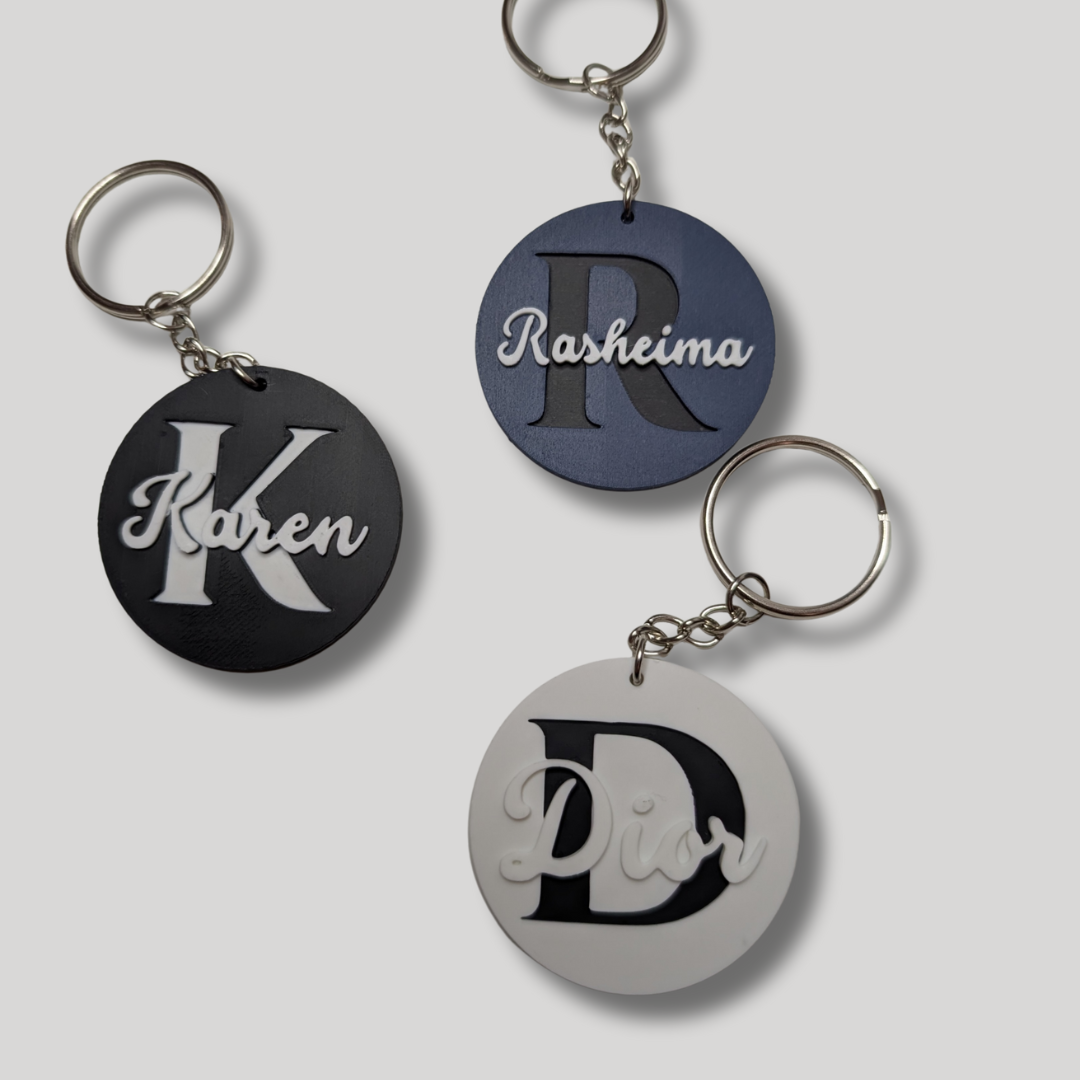 Three round keychains with personalized names 'Karen', 'Rasheima', and 'Diva' on a light gray background.