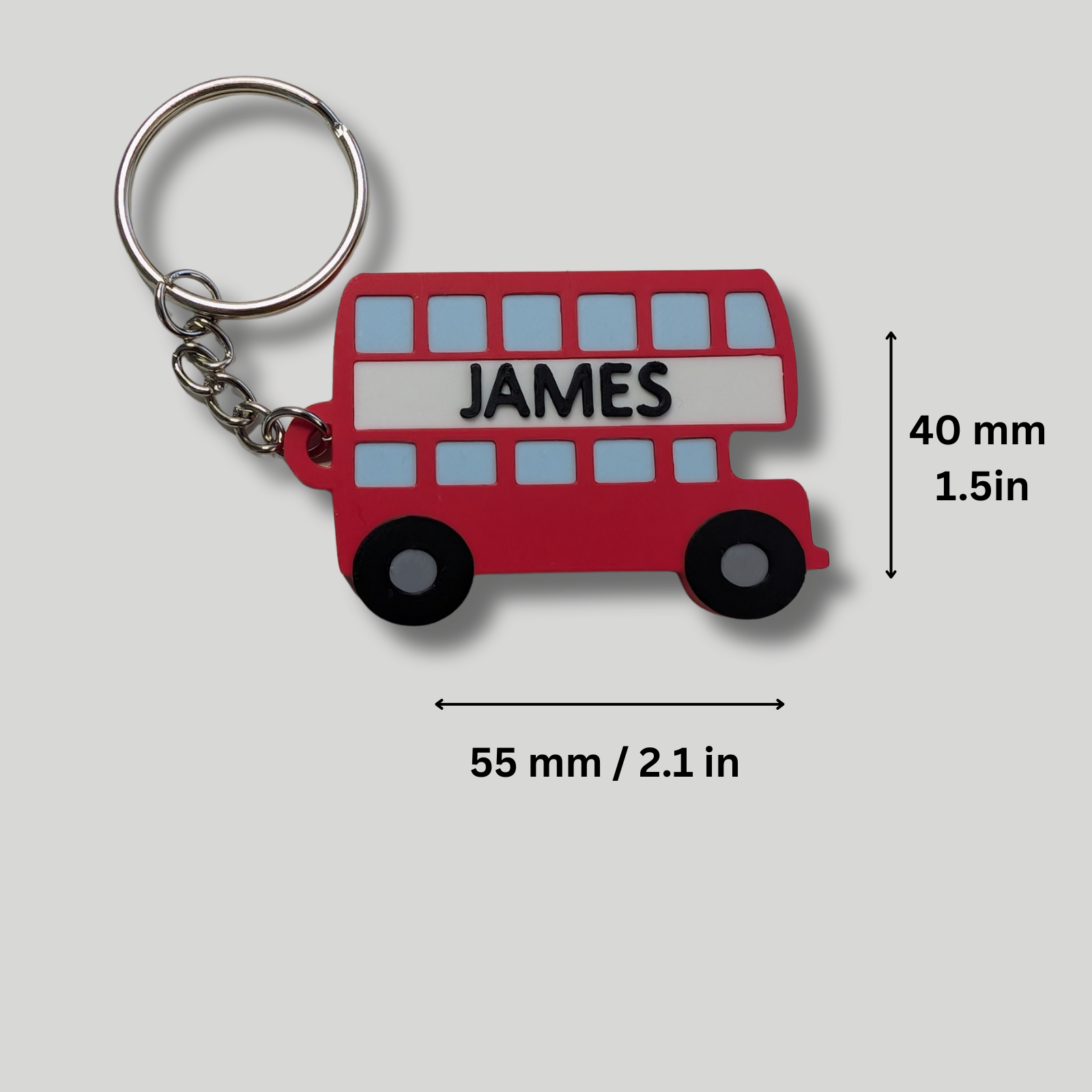 Red bus-shaped keychain with 'JAMES' on a gray background
